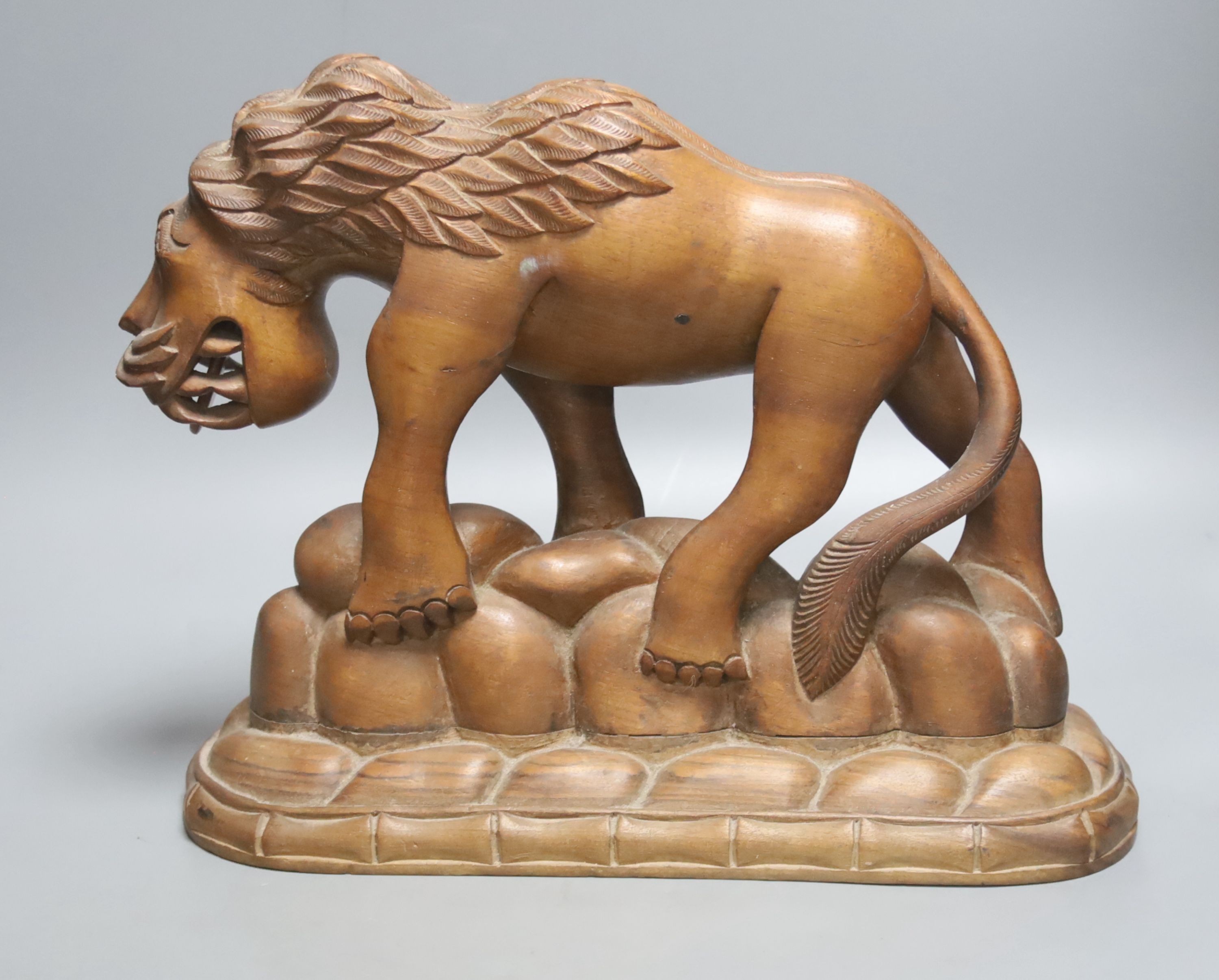 An Asian carved hardwood model of a lion, height 26cm